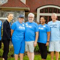 Alumni pose in front of the Alumni House